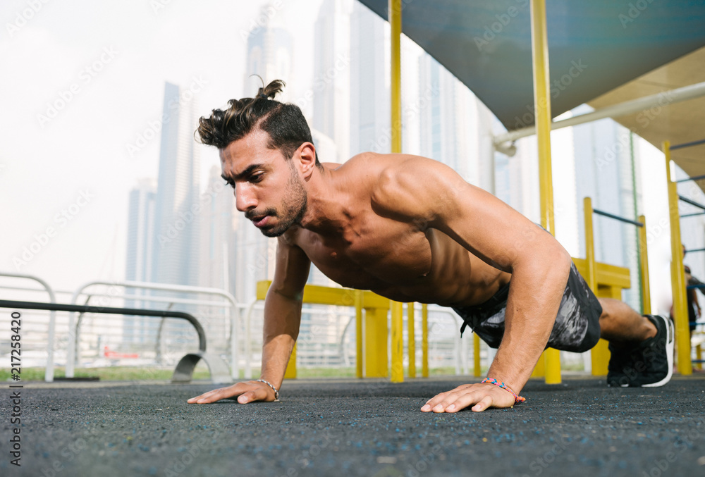 Obraz premium Young muscular arab athlete doing pushups otdoors in Dubai.