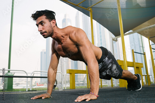 Young muscular arab athlete doing pushups otdoors in Dubai.