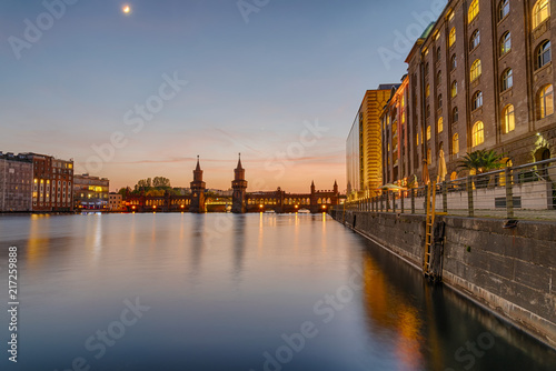 The banks of the river Spree in Berlin with the Oberbaum Bridge in the back after sunset