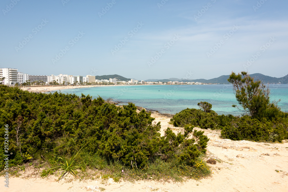 View to the beach of Cala Millor with the hotels and beach promenade with the hills and mountains in the background on the Spanish Mediterranean island Mallocra