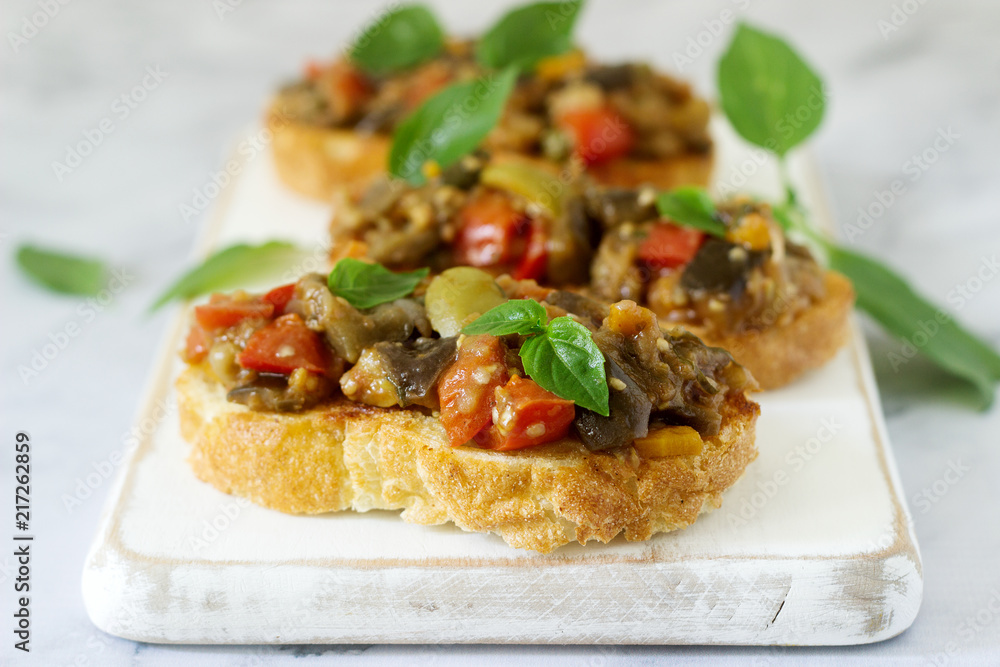 Bruschetta with caponata or ratatouille from various vegetables on a light background. Bruschetta with caponata or ratatouille from various vegetables on a light background.
