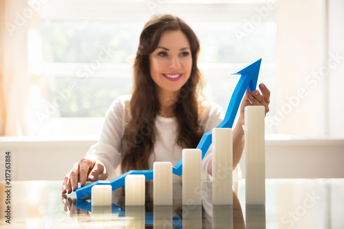 Increasing Graph In Front Of Businesswoman Holding Arrow photo