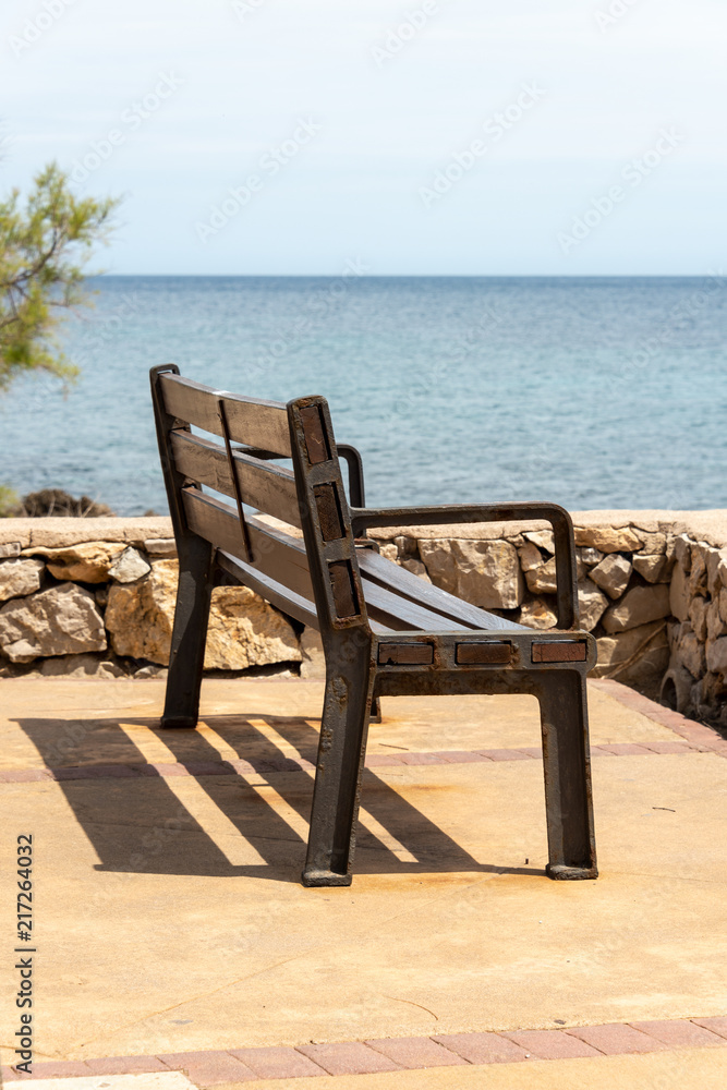 A bench on the seafront in the holiday resort Cala Millor with a beautiful view of Mittelmerr on the Spanish Balearic island Mallorca in front of a bright blue sky A bench on the seafront in the holiday resort Cala Millor with a beautiful view of Mittelmerr on the Spanish Balearic island Mallorca in front of a bright blue sky