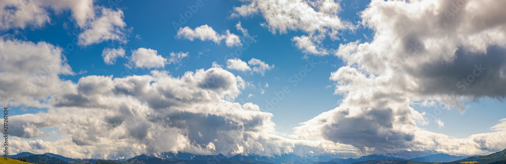 Obraz premium panorama of a gorgeous cloudscape above the mountain ridge. beautiful natural background of autumn sky