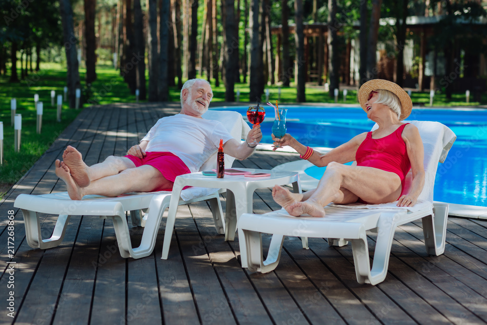 Retired couple. Couple of retired people feeling unbelievable while having rest lying on deck chair