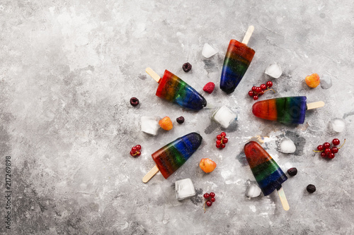 Rainbow colorful ice cream popsicle with wood stick on a gray background. Top view, copy space. Food background