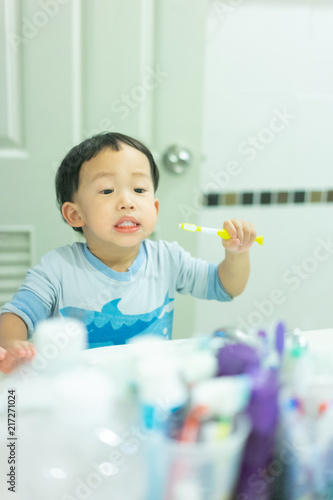 A boy brushes his teeth by himself in the restroom.