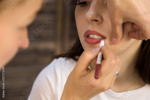 makeup artist doing lips makeup with pencil to young model