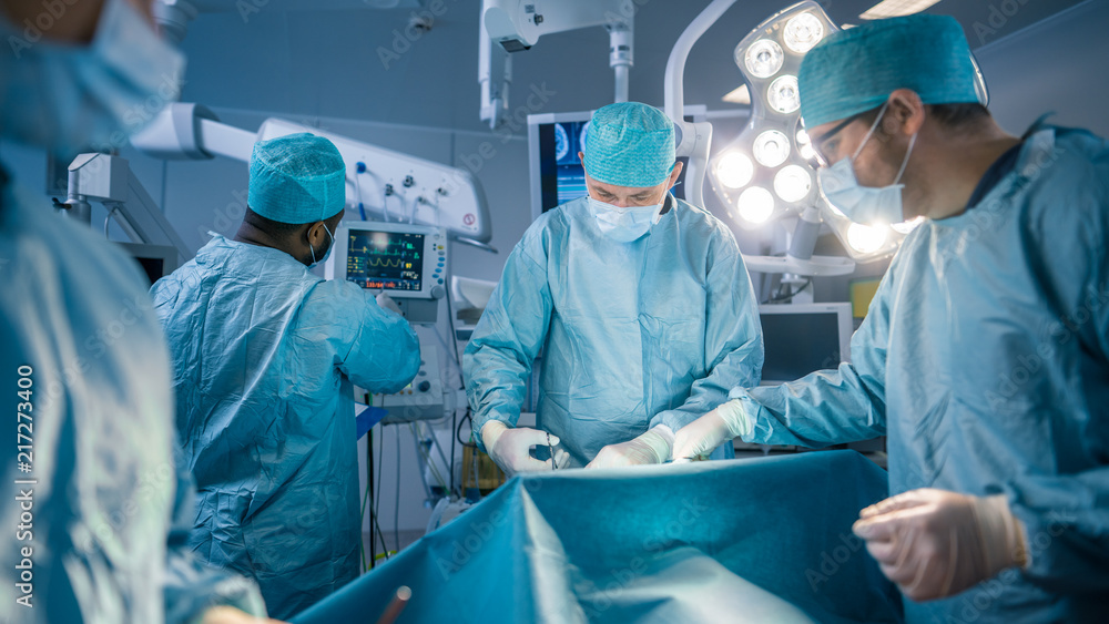 Diverse Team of Professional surgeon, Assistants and Nurses Performing Invasive Surgery on a Patient in the Hospital Operating Room. Real Modern Hospital with Authentic Equipment. Diverse Team of Professional surgeon, Assistants and Nurses Performing Invasive Surgery on a Patient in the Hospital Operating Room. Real Modern Hospital with Authentic Equipment.