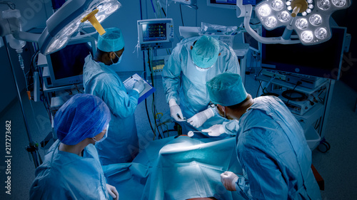 High Angle Shot of Diverse Team of Professional surgeon, Assistants and Nurses Performing Invasive Surgery on a Patient in the Hospital Operating Room. Real Modern Hospital with Authentic Equipment.