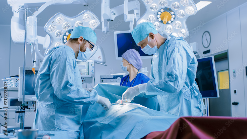In the Hospital Operating Room Diverse Team of Professional Surgeons and Nurses Suture Wound after Successful Surgery. In the Hospital Operating Room Diverse Team of Professional Surgeons and Nurses Suture Wound after Successful Surgery.