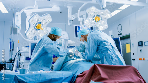 Diverse Team of Professional Surgeons Performing Invasive Surgery on a Patient in the Hospital Operating Room. Surgeons Use Instruments.