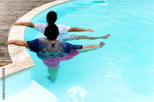 Two senior women doing aqua gym exercise in outdoor swimming pool. photo