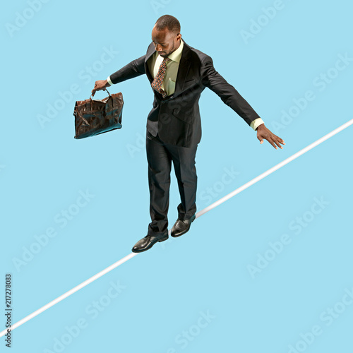 Fotografie Business man on tightrope concentrate to walking isolated on blue background