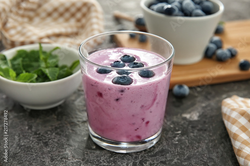 Glass of tasty blueberry smoothie on table
