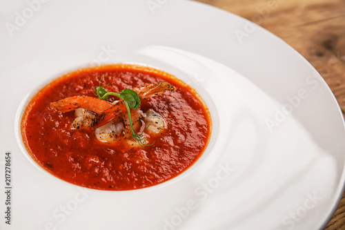 Tasty tomato soup with shrimps in plate, closeup