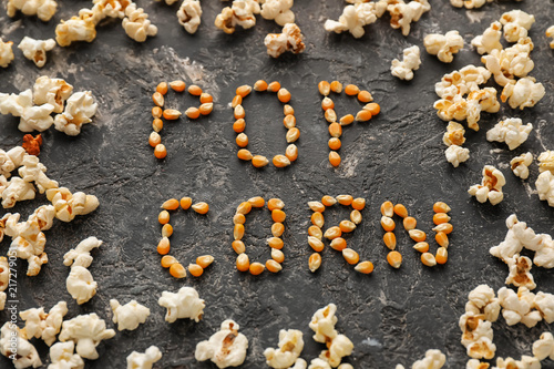 Delicious popcorn and words made of kernels on grunge table