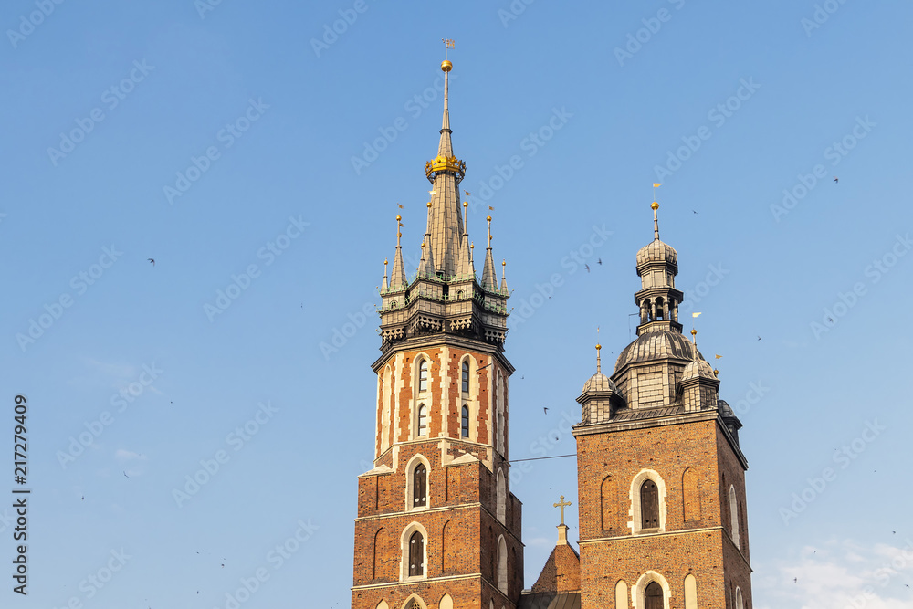 Detail of domes of Gothic Saint Mary Basilica in city center of Krakow, Poland, at evening with Swallows flying