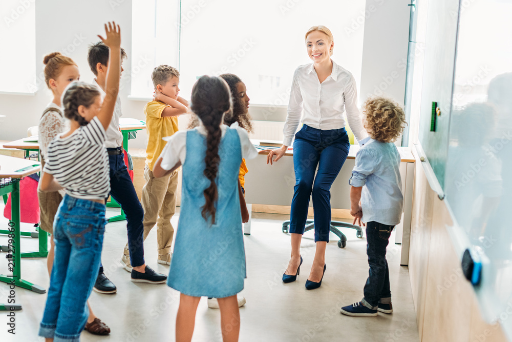 group of classmates standing around teacher at classroom and having fun group of classmates standing around teacher at classroom and having fun