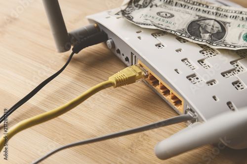 A wireless modem router, a dollar(USA) note and Ethernet cable.  This image can be used to represent the cost of internet data plans in America or net neutrality. 