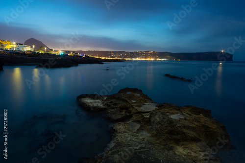 Night view of the illuminated city. With sea water and clouds in long exposure