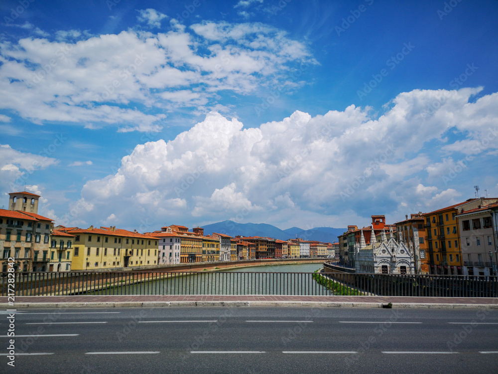 landscape with clouds and bridge over river in italian town