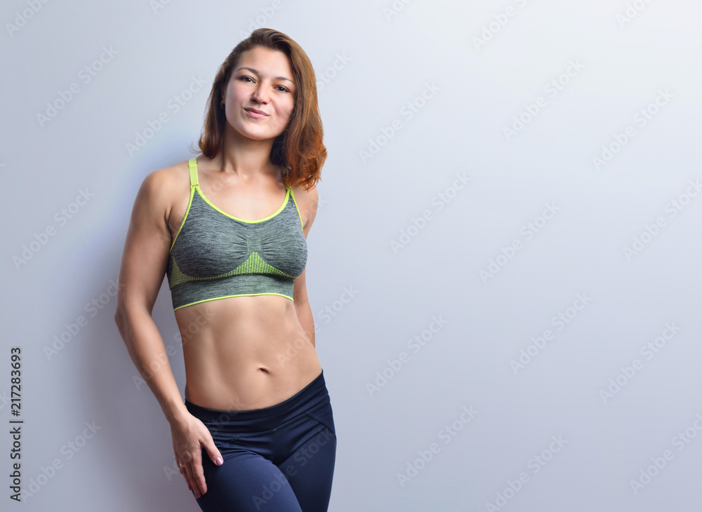 Fototapeta premium Beautiful fitness woman showing abdominal muscles on a studio background.