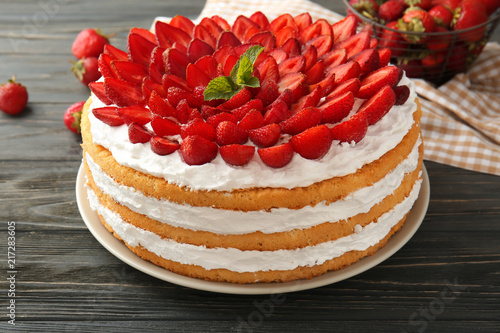 Delicious cake with strawberries on wooden table, closeup