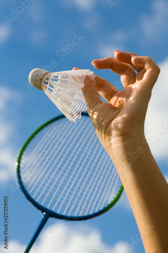 A female hand holds a shuttlecock against the sky. photo