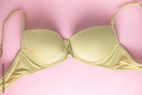 Beige bra on pink background as symbol of female breast disease. Breast cancer awareness month. Minimalistic style. Top view. Flat lay.