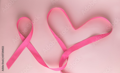 Pink ribbon and Heart on pink background as symbol of female breast disease. Breast cancer month awareness tape. Minimalistic style. Top view. Flet lei. Place for text. Copy space. photo