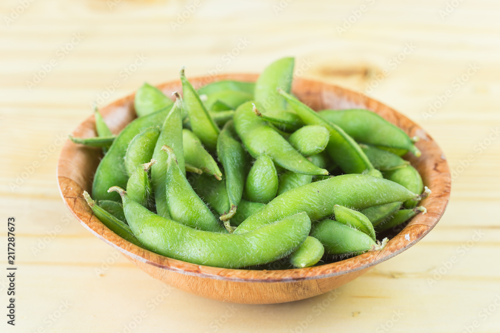 Fresh steamed edamame sprinkled with sea salt on a rustic tabletop. Fresh steamed edamame sprinkled with sea salt on a rustic tabletop.