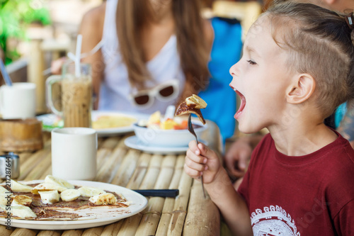 boy eating pancake with banana and chocolate