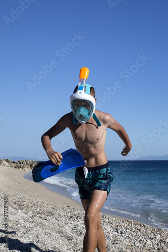 Teenager with mask and flippers walking at sea coast. photo