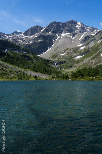 Alpine lake into the wild nature, between pines, rock and mountains