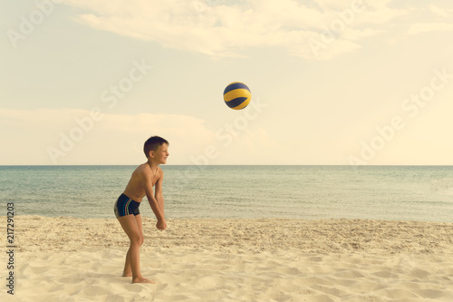 Boy playing and running ball of valleyball at the sea beach