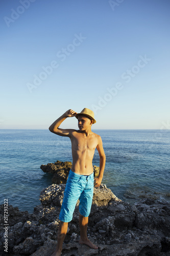 Teenager looking  on rocky coast at sea.