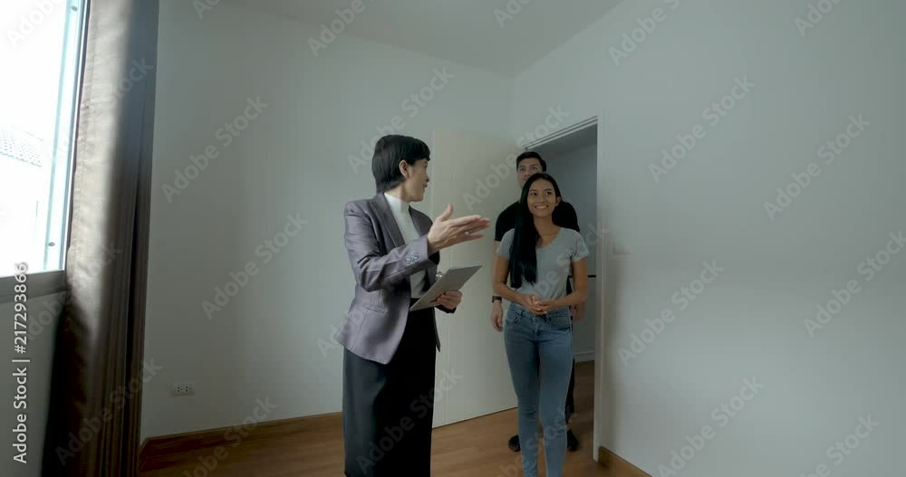Professional real estate agent shows modern house to a beautiful young asian couple who are in the market for purchasing, renting New Home. Professional real estate agent shows modern house to a beautiful young asian couple who are in the market for purchasing, renting New Home.