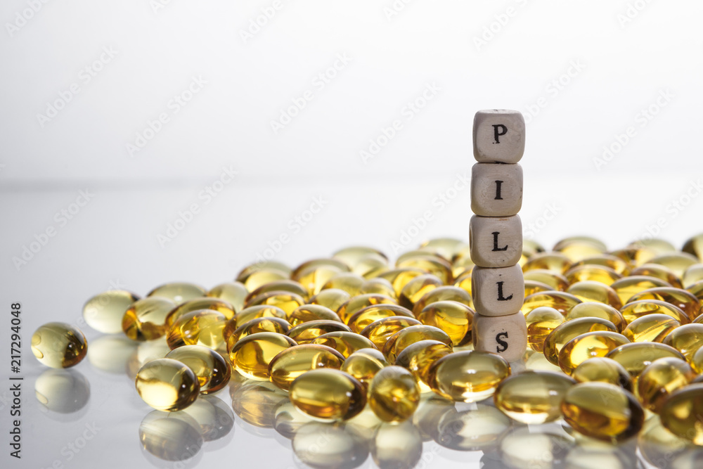 Word pills from the letters of cubes and Lecithin gel pills on light background.