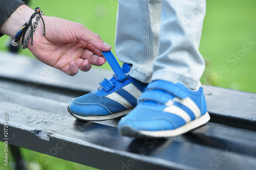 Bild auf Leinwand man tying velcro snickers on child