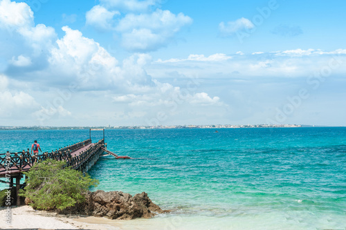 The wooden pier goes into the blue ocean. Tropical landscape with turquoise sea on the island of Zanzibar