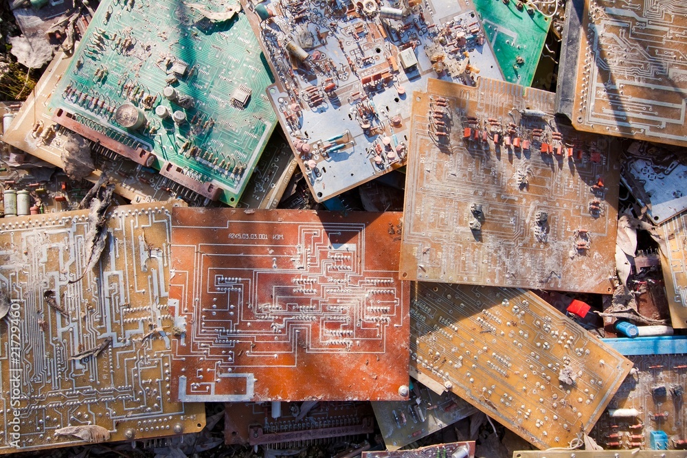 Many old, used and broken electronic circuit chips thrown in the dirt; background texture photo
