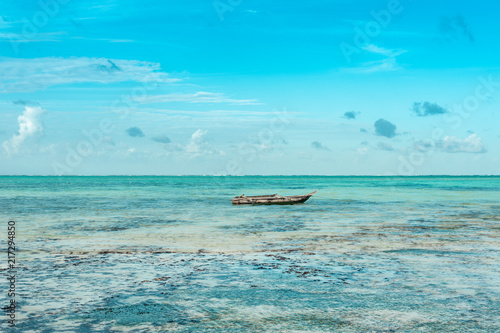 Fototapeta Naklejka Na Ścianę i Meble -  Fisherman's boat swinging on turquoise waves in the Indian ocean near the shore of the island of Zanzibar