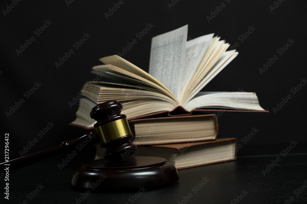 Judge gavel beside pile of books on wooden background Judge gavel beside pile of books on wooden background