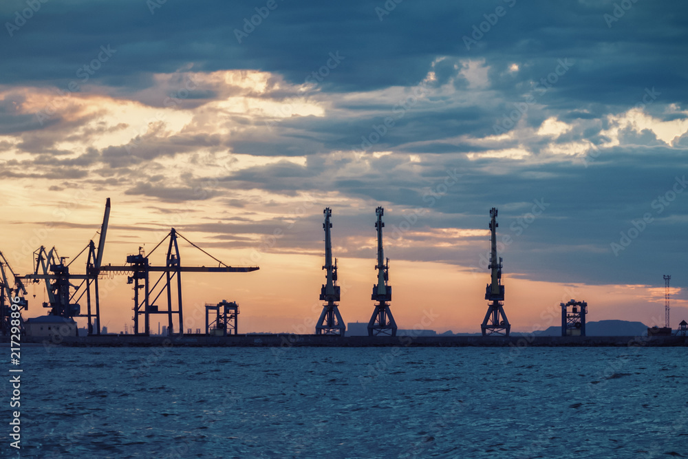 Silhouettes of sea port cranes at sunrise, sunset Silhouettes of sea port cranes at sunrise, sunset