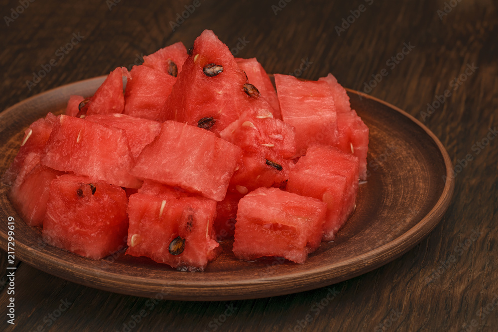 The flesh of watermelon cut into cubes in a clay plate The flesh of watermelon cut into cubes in a clay plate
