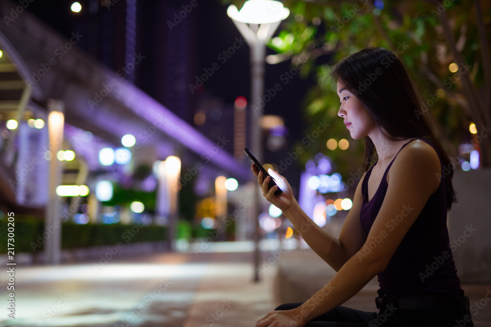 Beautiful Asian Woman Outdoors At Night Using Mobile Phone Beautiful Asian Woman Outdoors At Night Using Mobile Phone