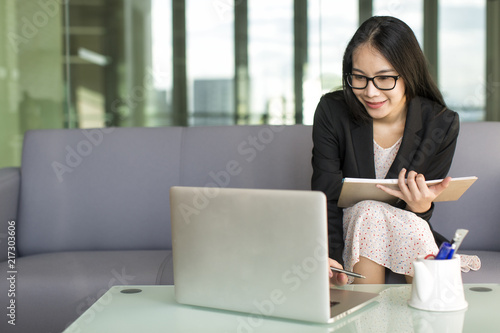 Young Asian businesswoman in suit and sweet dress working with laptop at office, professional working proficiency with smile and happy.