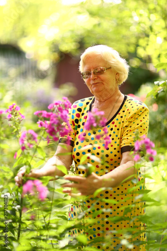 healthy pensioner woman in garden watering seed bed