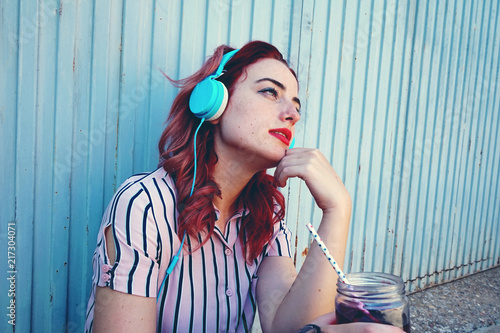 Canvastavla Mujer joven y pelirroja escuchando música con sus auriculares